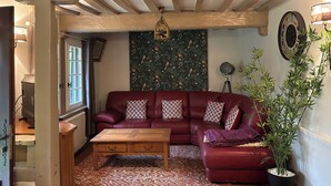 A cozy living room with a red leather sofa, a wooden coffee table, and a patterned wall. - Thatched cottage (Tourville-sur-Pont-Audemer)