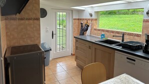 A kitchen with a dishwasher, a sink, and a window with a view of the garden. - Thatched cottage (Tourville-sur-Pont-Audemer)