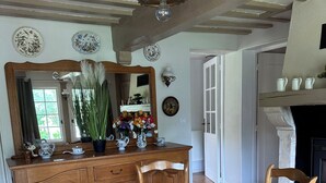 A dining room with a wooden table and chairs, a large mirror, and a decorative vase with flowers. - Thatched cottage (Tourville-sur-Pont-Audemer)