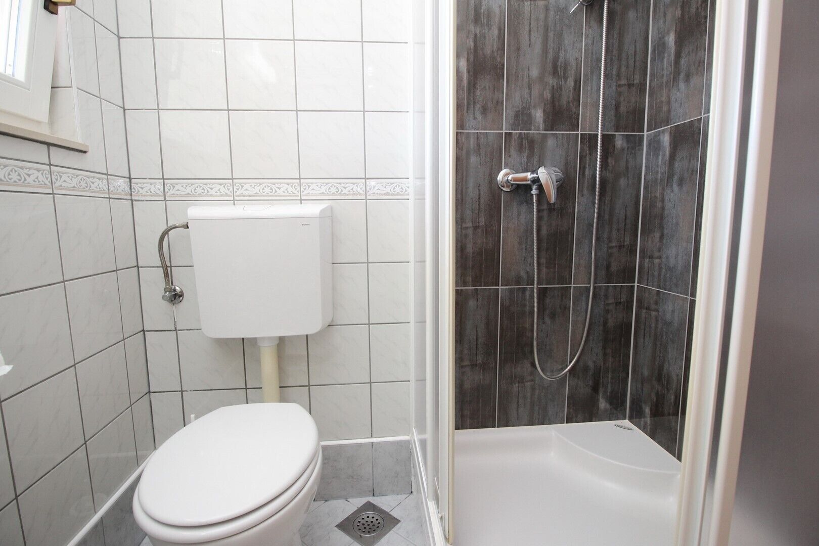 A bathroom with a toilet, a shower, and a sink.
