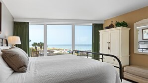Ein Schlafzimmer mit einem großen Bett, Blick auf den Strand und einem weißen Kleiderschrank.