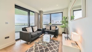 A modern living room with two sofas, a glass coffee table, and a view of the city.
