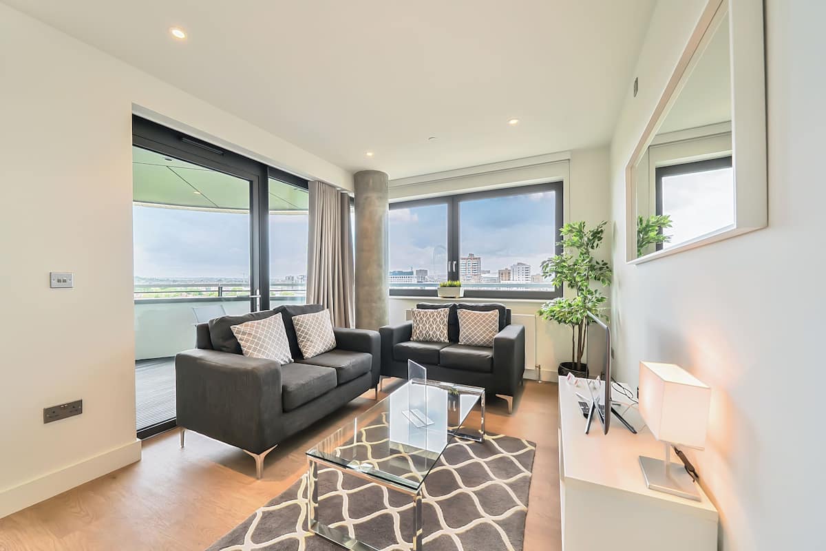 A modern living room with two sofas, a glass coffee table, and a view of the city.