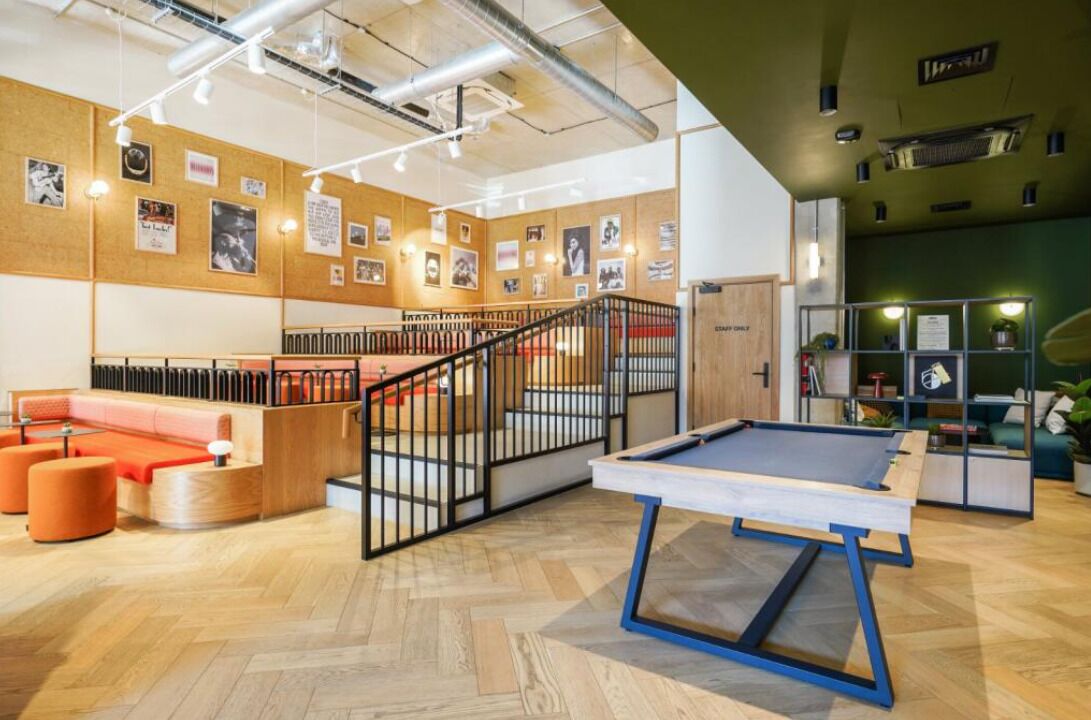 Un espace intérieur moderne doté d’une table de billard, de planchers en bois et d’un escalier avec une rampe.