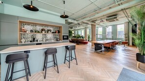 A modern kitchen with a bar area, wooden flooring, and large windows.