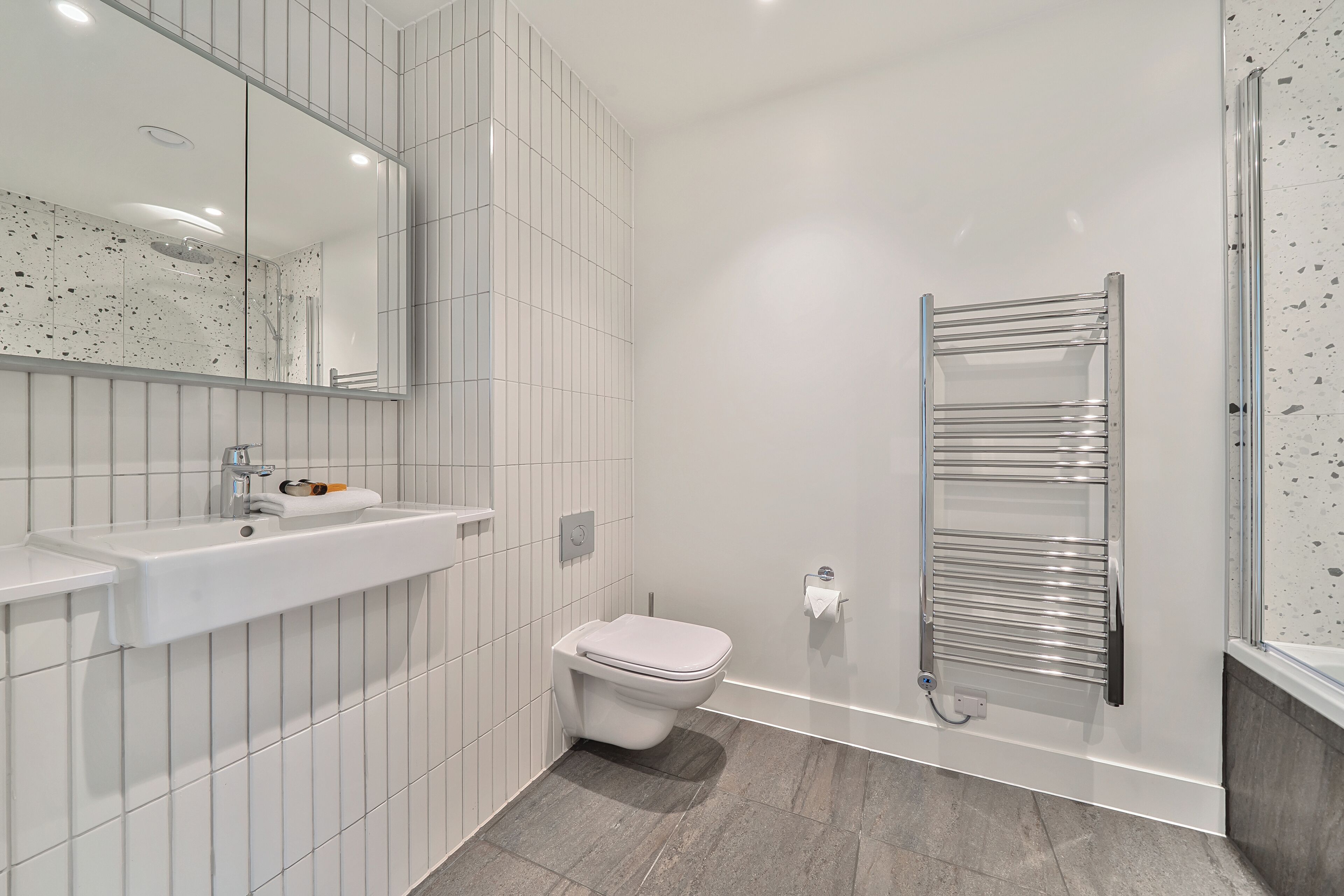 Une salle de bain moderne avec un lavabo blanc, des toilettes et une cabine de douche en verre.