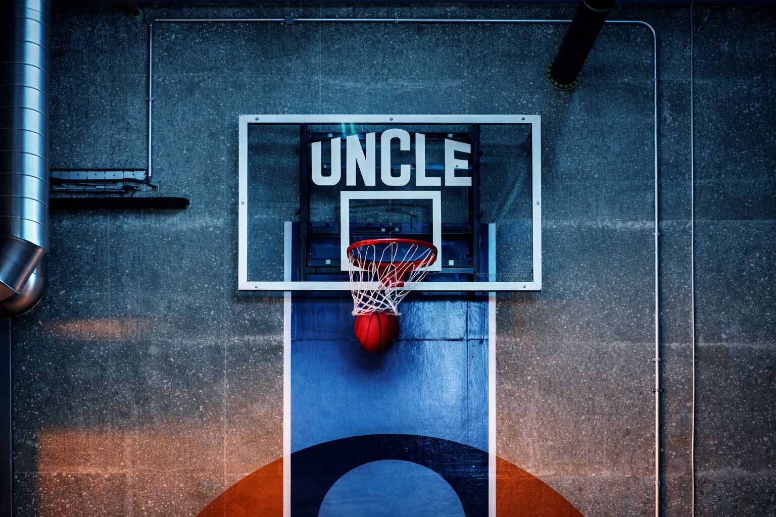 Ein Basketballkorb mit der Aufschrift 'UNCLE' auf der Rückwand.