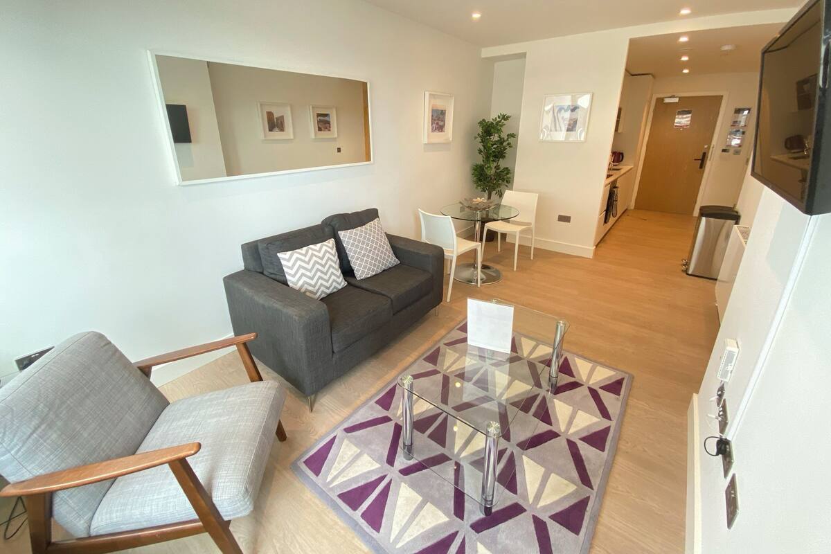 A modern living room with a grey sofa, a small table, and a patterned rug.