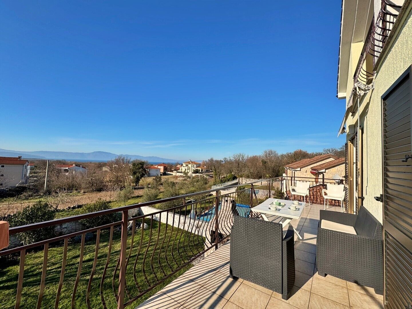 Un balcón con vista a una piscina y casas a lo lejos.