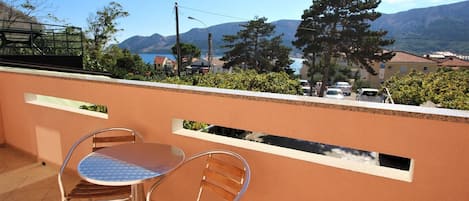 En balkon med to stole og et bord, der giver udsigt over et bjerglandskab med klar himmel.