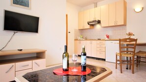 Una cocina moderna con armarios de colores claros, un televisor de pantalla plana montado en la pared y una zona de comedor con mesa y sillas.