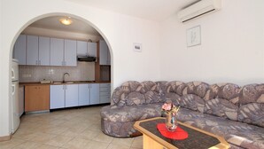 A living room with a sofa and a coffee table, a kitchen with cabinets and a sink, and an arched doorway leading to the kitchen. - Apartment Lucijana No.4 - with Balcony, 150 m from the Beach (Baska)