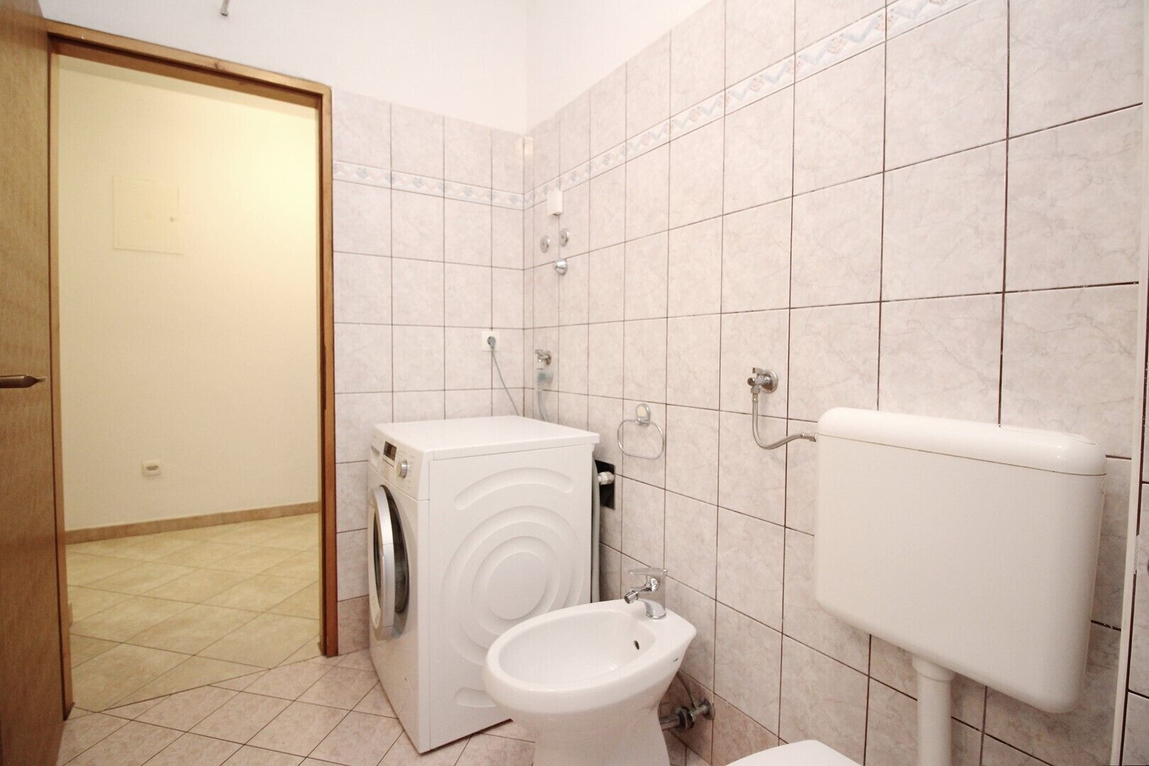 Un baño pequeño con lavadora, inodoro y lavamanos.