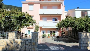 A multi-story building with a stone entrance gate, potted plants, and a clear sky.