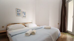 A neatly made bed with white linens and two rolled towels, a wooden headboard, and two framed pictures on the wall. - Studio Mul No.4 Bs - for 4 Persons, with Terrace (Baska)
