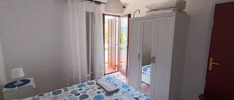 A bedroom with a bed, a wardrobe, and a door leading to a balcony.