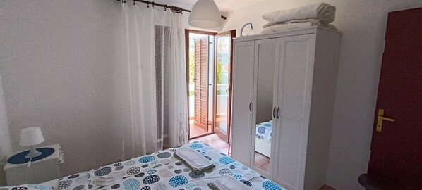 A bedroom with a bed, a wardrobe, and a door leading to a balcony.