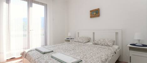 A bedroom with a bed, bedside tables, a nightstand, a lamp, and a picture frame on the wall.