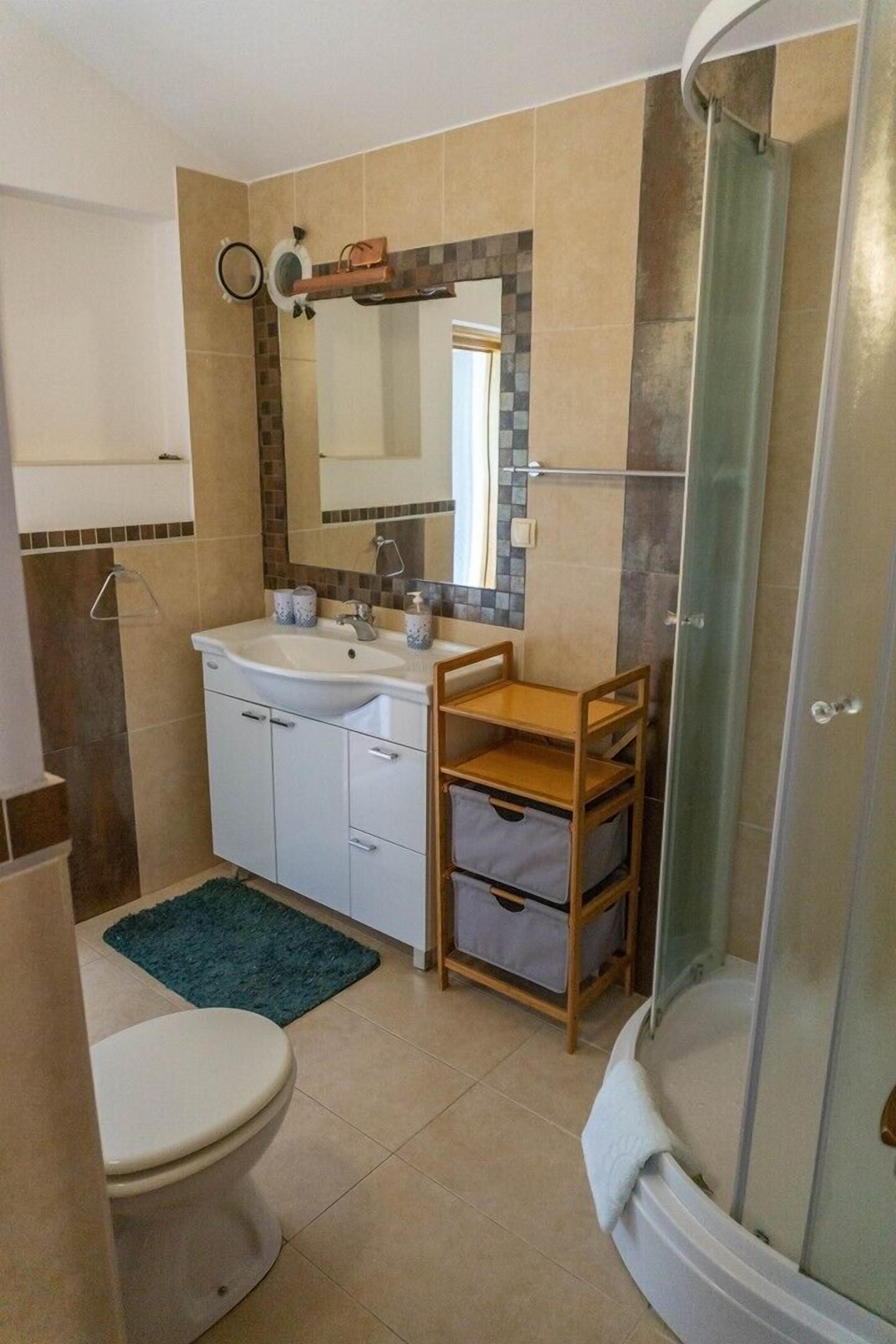 Ein Badezimmer mit Waschbecken, Spiegel, Toilette und Dusche.