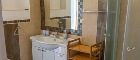 Ein Badezimmer mit Waschbecken, Spiegel, Toilette und Dusche.