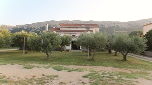 A two-story building with a tiled roof, surrounded by olive trees and a gravel path. - Apartment Petrica No.2 - with Balcony, located in the peaceful village of Jurandvor near Baska (Jurandvor)