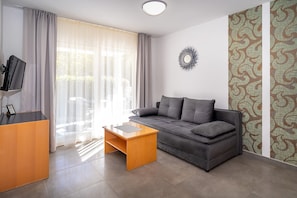 A modern living room with a grey sofa, a wooden coffee table, and a TV on a stand.