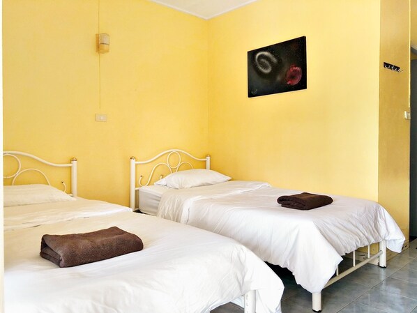 Una habitación con dos camas individuales, cada una con ropa blanca y una toalla marrón sobre una cama.