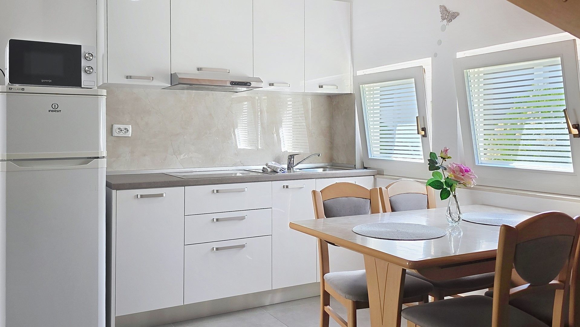 Una cocina moderna con armarios blancos, microondas integrado y un comedor con mesa y sillas.