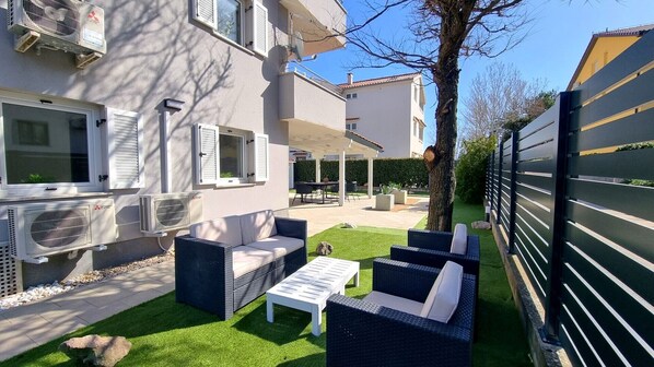 A residential property with a patio area featuring outdoor furniture, a lawn, and a covered seating area.