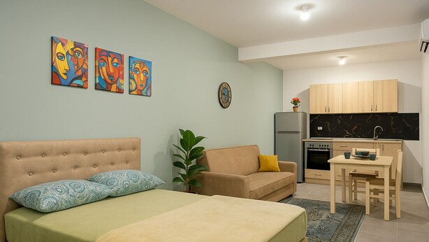 A modern apartment with a bed, a sofa, a dining table, and a kitchen area.