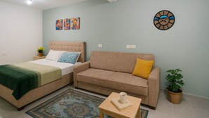 A bedroom with a bed, a sofa, a coffee table, and a wall clock.