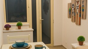 A dining area with a white table, blue and orange plates, and a window with frosted glass doors.