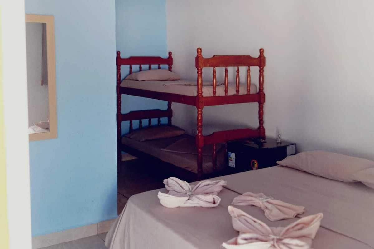 A room with bunk beds, a single bed, a ceiling fan, and a mirror on the wall.