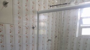 A bathroom with a toilet, a shower with a glass door, and floral-patterned tiles.