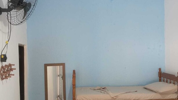 A room with a bunk bed, a ceiling fan, a wall-mounted fan, and a mirror.