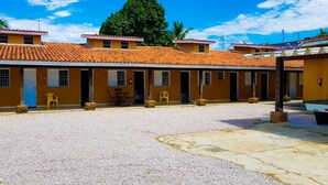 A row of yellow buildings with red-tiled roofs, a gravel courtyard, and a pool table.