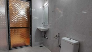A modern bathroom with a toilet, sink, and shower. - Aditya Forest Eco Resort (Abu Road)