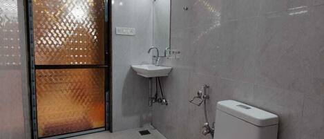 Et moderne badeværelse med toilet, håndvask og bruser.