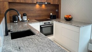 Una cocina moderna con encimeras de granito, armarios de madera y horno integrado.