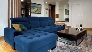 Una sala de estar moderna con un sofá seccional azul, piso de madera y una mesa de centro oscura.