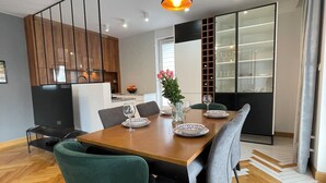 Un comedor moderno con mesa de madera, sillas verdes e iluminación colgante.