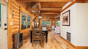 Een houten interieur met een eethoek, houten wanden en een groot raam.