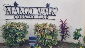 Skilt for Mango Walk Country Club med en solcelle foran.