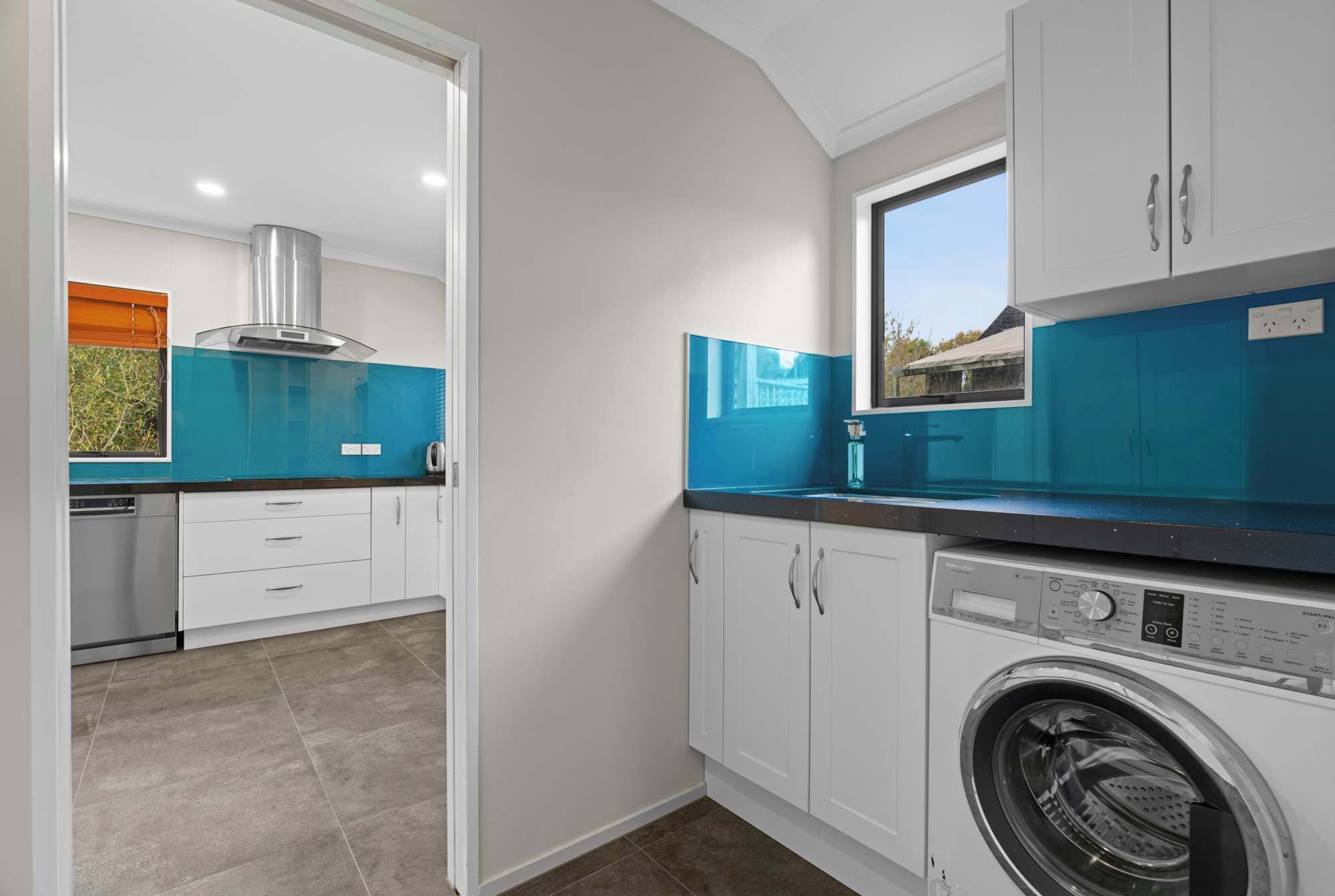 A compact kitchen with white cabinets, a built-in oven, and a window above the sink.