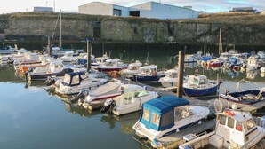 A marina with multiple boats docked, a building in the background, and a stone wall. - 5 Ashcroft Mews (Seaham)