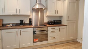 A modern kitchen with white cabinets, stainless steel appliances, and a wooden countertop. - 5 Ashcroft Mews (Seaham)