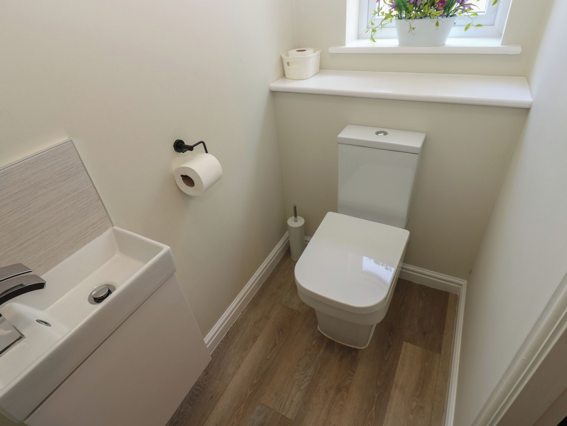 Ein kleines Badezimmer mit Toilette, Bidet und einem Fenster mit Pflanzen.