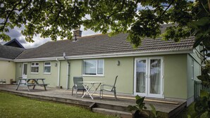 Ein Haus mit einer Terrasse, einem Tisch und Stühlen.