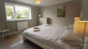 Ein Schlafzimmer mit einem Bett, einem Schminktisch, einem Stuhl, einem Fenster und einer Lampe.