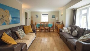 Ein Wohnzimmer mit zwei Ledersofas, einem Holzessttisch und einem großen Gemälde an der Wand.